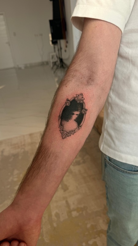 Ornate mirror frame tattoo holding a landscape, forearm